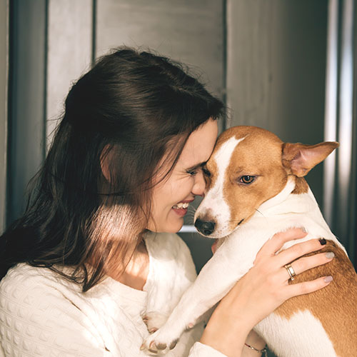 beautiful smiling woman hugging her dog at home